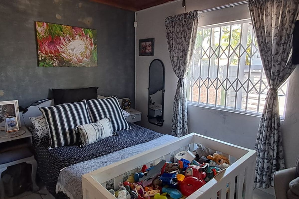 A bedroom featuring a textured accent wall, security gate on the window, and standard finishes.