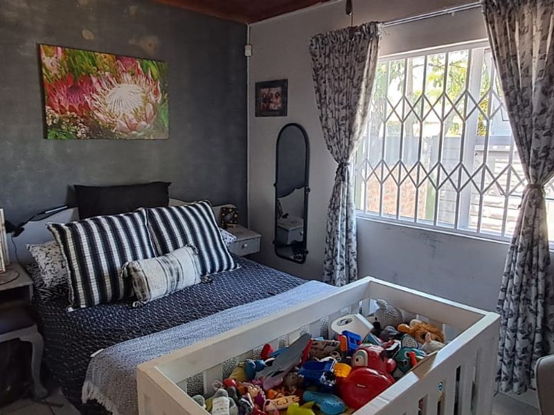 A bedroom featuring a textured accent wall, security gate on the window, and standard finishes.