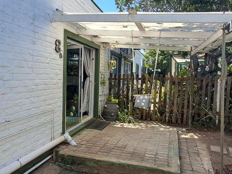 A small paved patio area featuring a pergola structure and direct access to the interior via a sliding glass door.