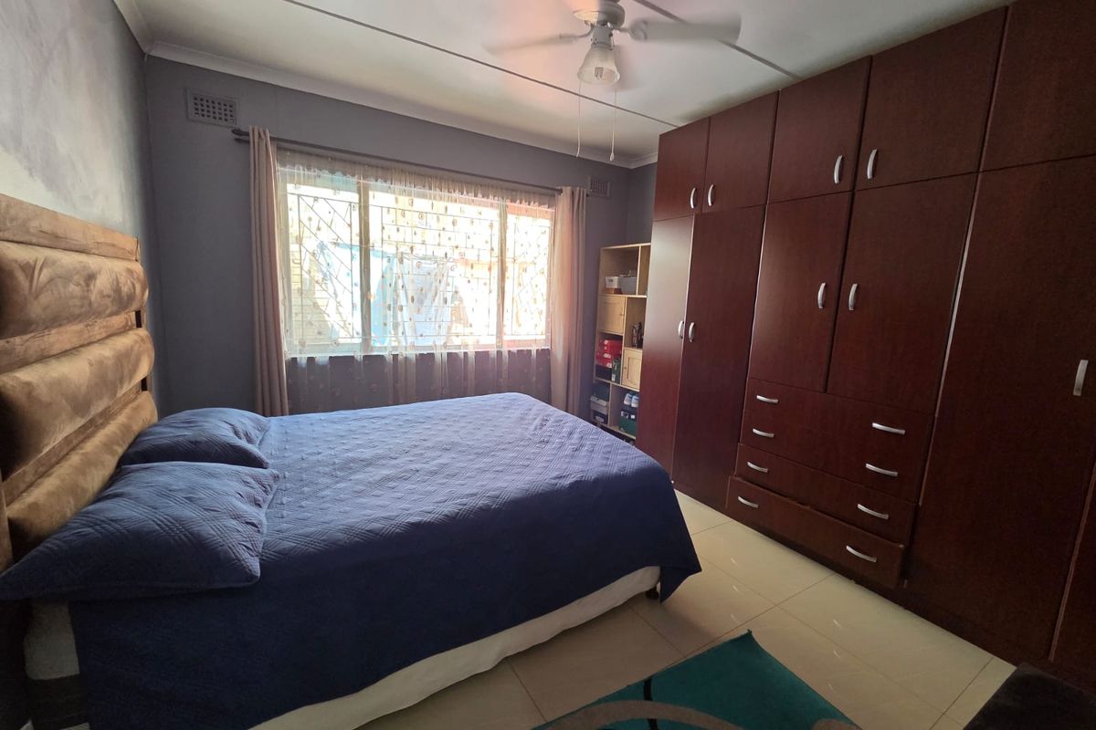 A functional bedroom featuring extensive built-in wooden cabinetry, tiled flooring, and a ceiling fan, providing ample storage and comfortable living space.