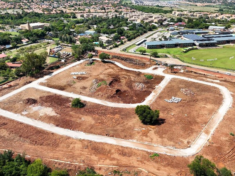 Aerial view of a residential development site showing cleared land, internal road infrastructure, and surrounding suburban neighborhood.