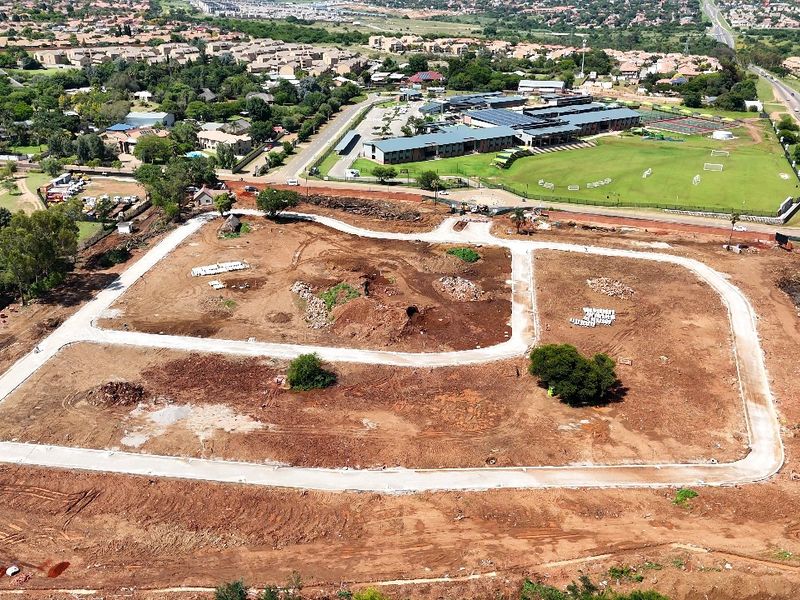 Aerial view of a residential development site featuring cleared land and newly constructed internal paved roads, ready for future building projects.
