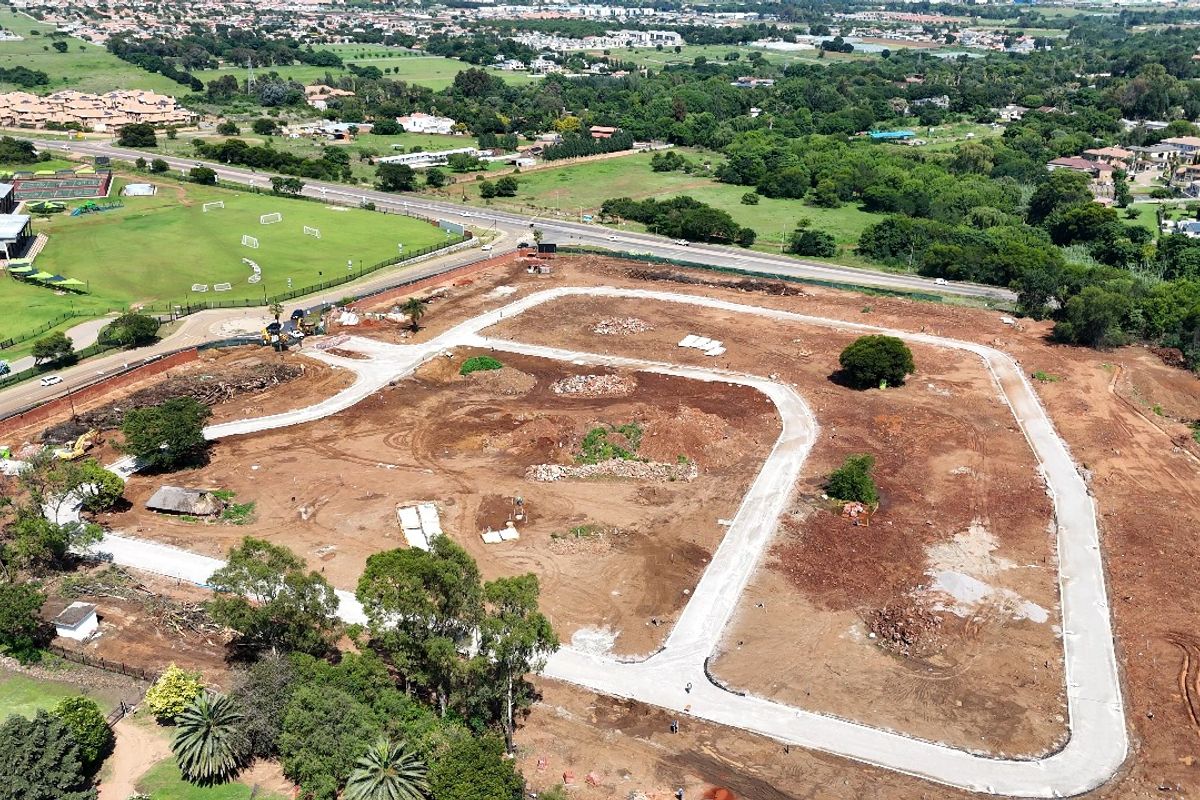 Aerial view of a residential development site showing cleared land, established road infrastructure, and surrounding suburban landscape.