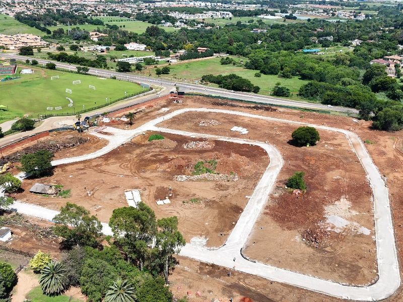 Aerial view of a residential development site showing cleared land, established road infrastructure, and surrounding suburban landscape.