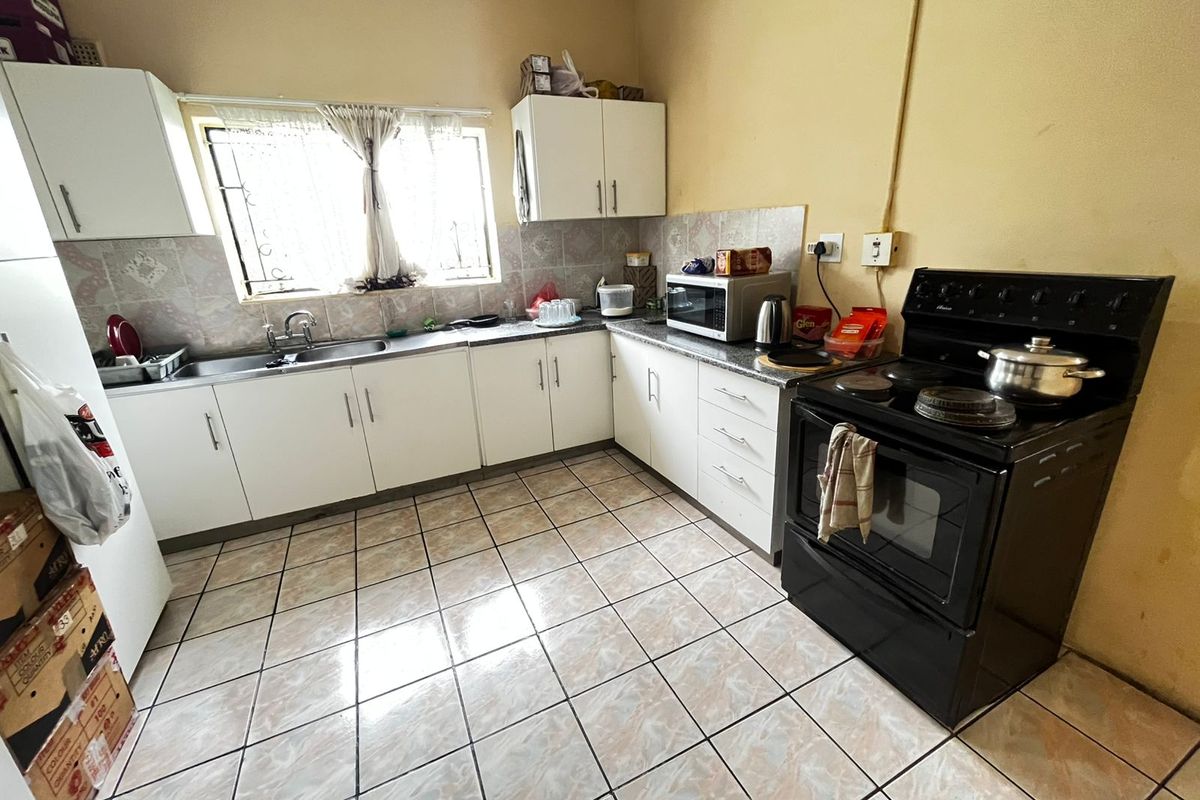 Functional kitchen featuring white cabinetry, tiled flooring, a tiled backsplash, and a freestanding stove, offering a practical layout for daily meal preparation.
