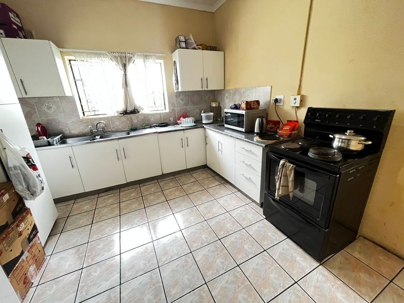 Functional kitchen featuring white cabinetry, tiled flooring, a tiled backsplash, and a freestanding stove, offering a practical layout for daily meal preparation.