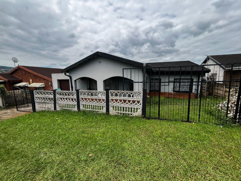 Front view of a single-story house featuring a tiled roof, covered porch, and secure perimeter fencing with a wrought iron gate.