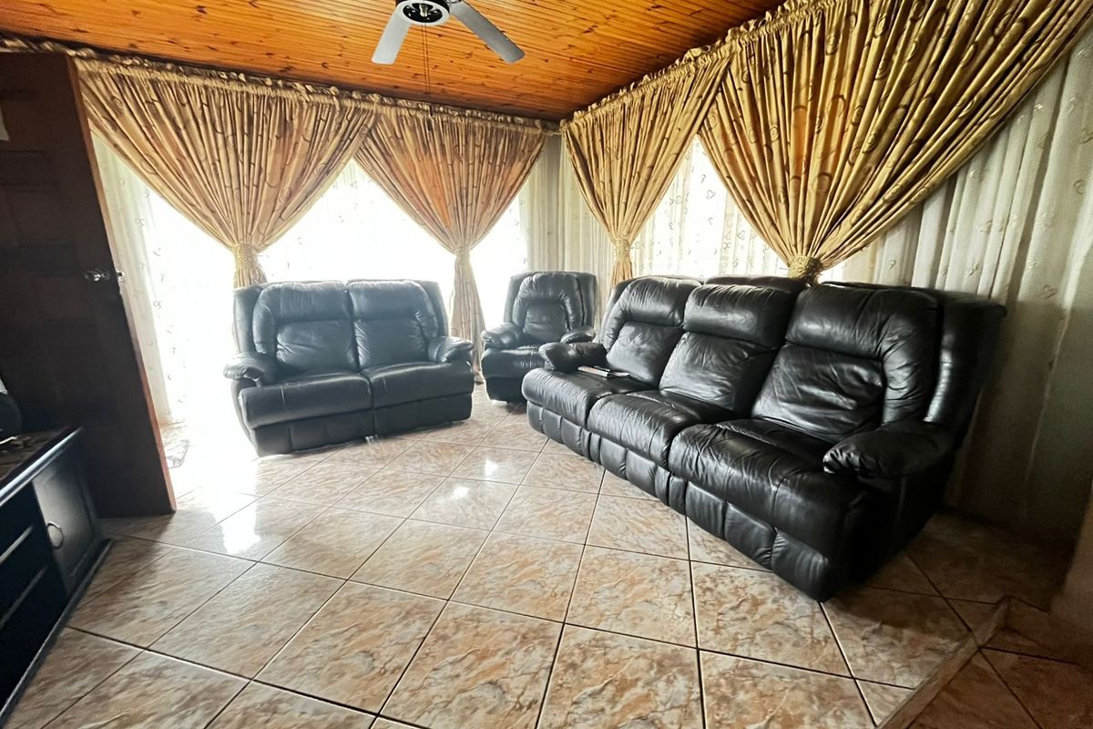 Living room featuring a timber-clad ceiling with a central fan and tiled flooring throughout.