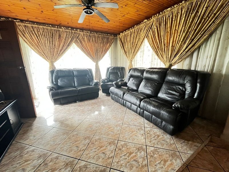 Living room featuring a timber-clad ceiling with a central fan and tiled flooring throughout.