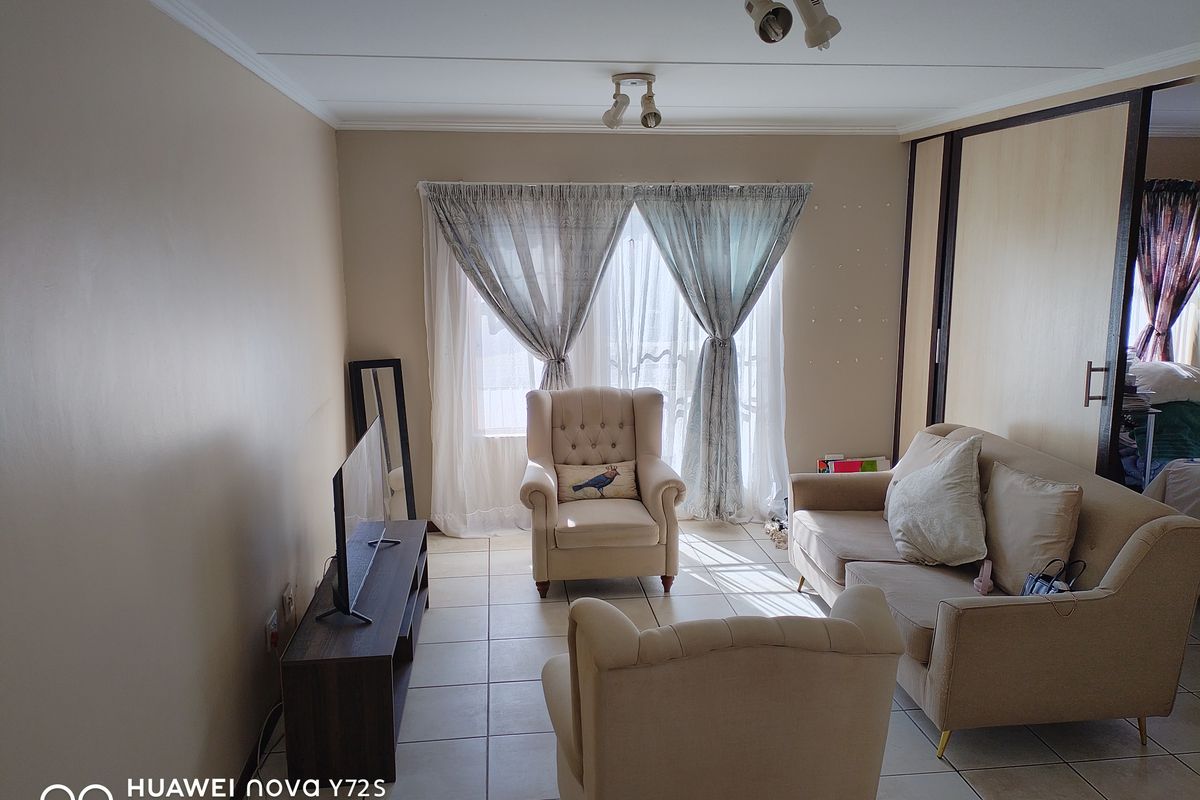 A living room featuring tiled flooring, built-in sliding door wardrobes, and ceiling-mounted spotlights, offering a functional and neutral living space.