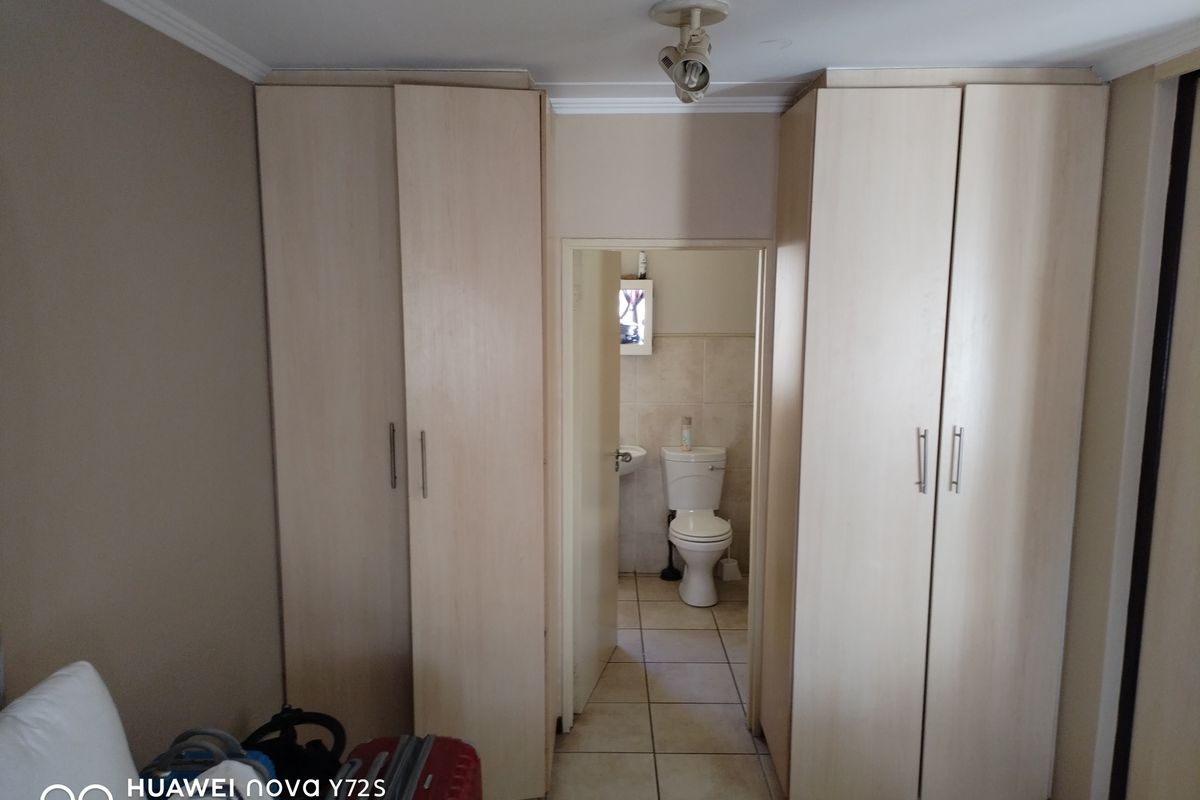 Bedroom featuring built-in cupboards with a direct view into an en-suite bathroom with tiled flooring.