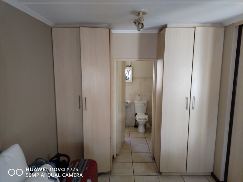 Bedroom featuring built-in cupboards with a direct view into an en-suite bathroom with tiled flooring.