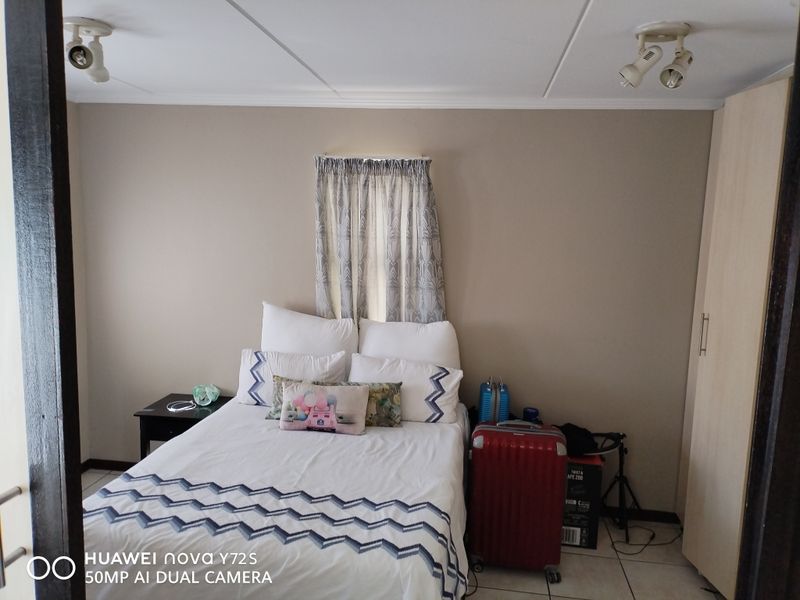 A bedroom featuring tiled flooring, built-in wardrobe storage, and ceiling-mounted spotlight fixtures.