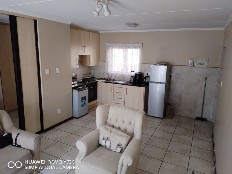 Open-plan kitchen and living area featuring tiled flooring, built-in cabinetry, and a functional kitchen layout with integrated appliances.