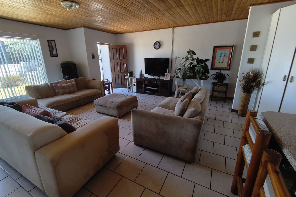 Spacious living room featuring ceramic tiled flooring and a warm timber tongue and groove ceiling, providing a comfortable and functional family living space.
