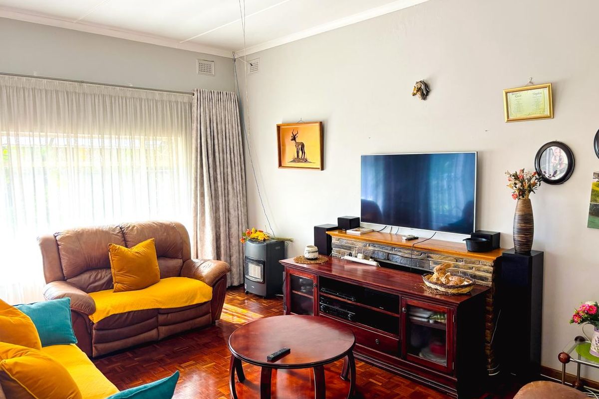 A comfortable living room featuring classic parquet flooring, a stone-clad feature wall, and a ceiling fan, creating a warm and inviting atmosphere.