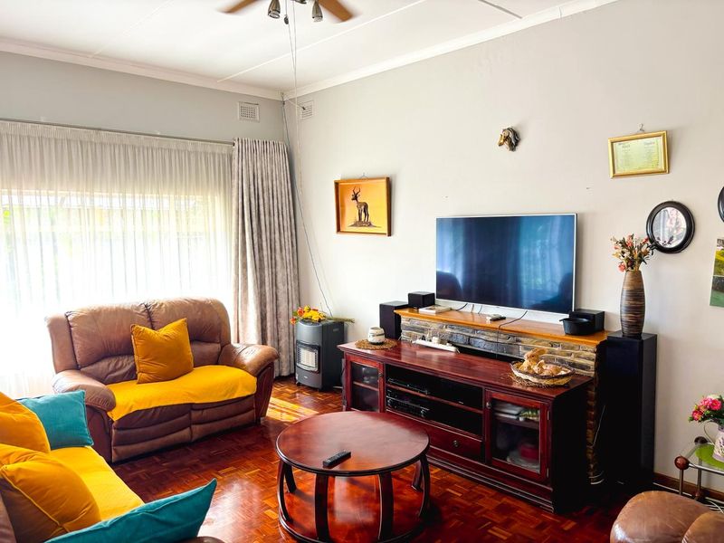A comfortable living room featuring classic parquet flooring, a stone-clad feature wall, and a ceiling fan, creating a warm and inviting atmosphere.