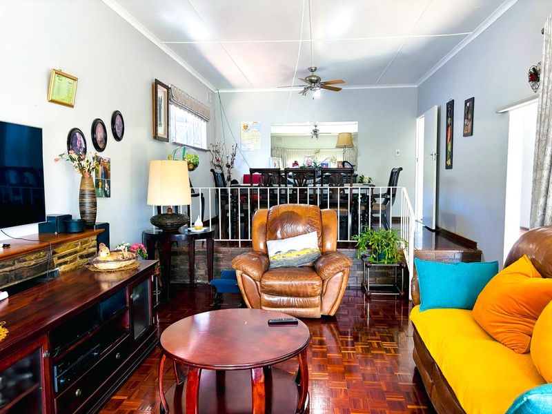 Open plan living and dining area featuring traditional parquet flooring, a brick partition wall, and a metal balustrade separating the split-level spaces.