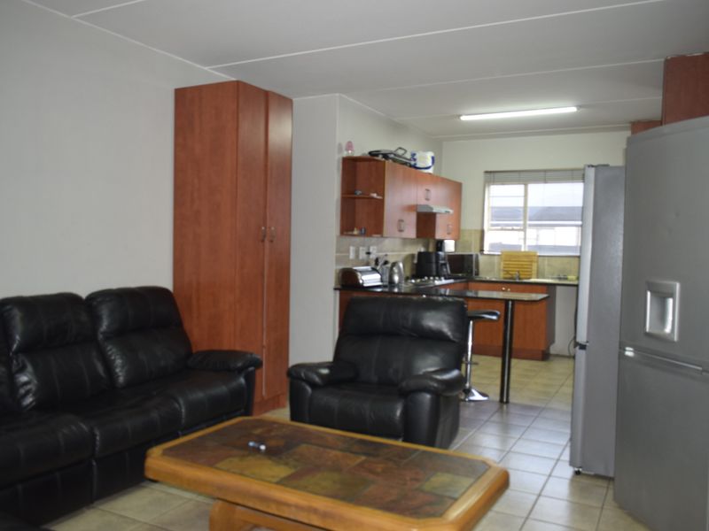 Open-plan living and kitchen area featuring tiled flooring, built-in cabinetry, and a functional kitchen layout.