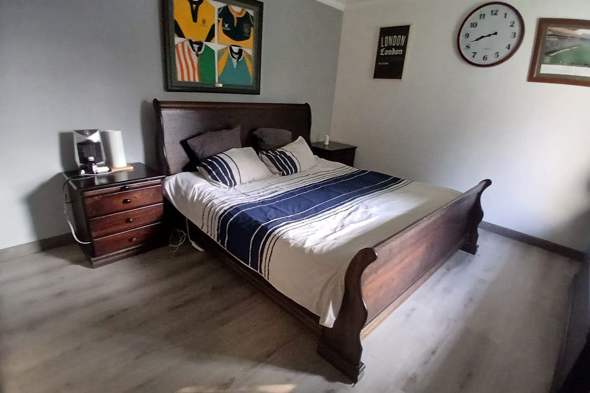 A bedroom featuring light-toned laminate flooring and neutral wall finishes.