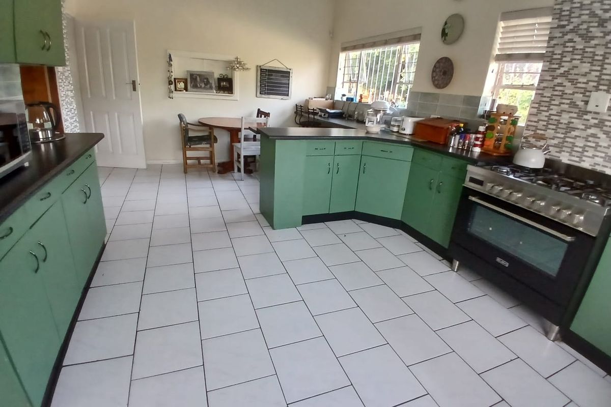 A functional kitchen featuring green cabinetry, a gas stove with oven, tiled flooring, and a tiled backsplash with natural light from windows.