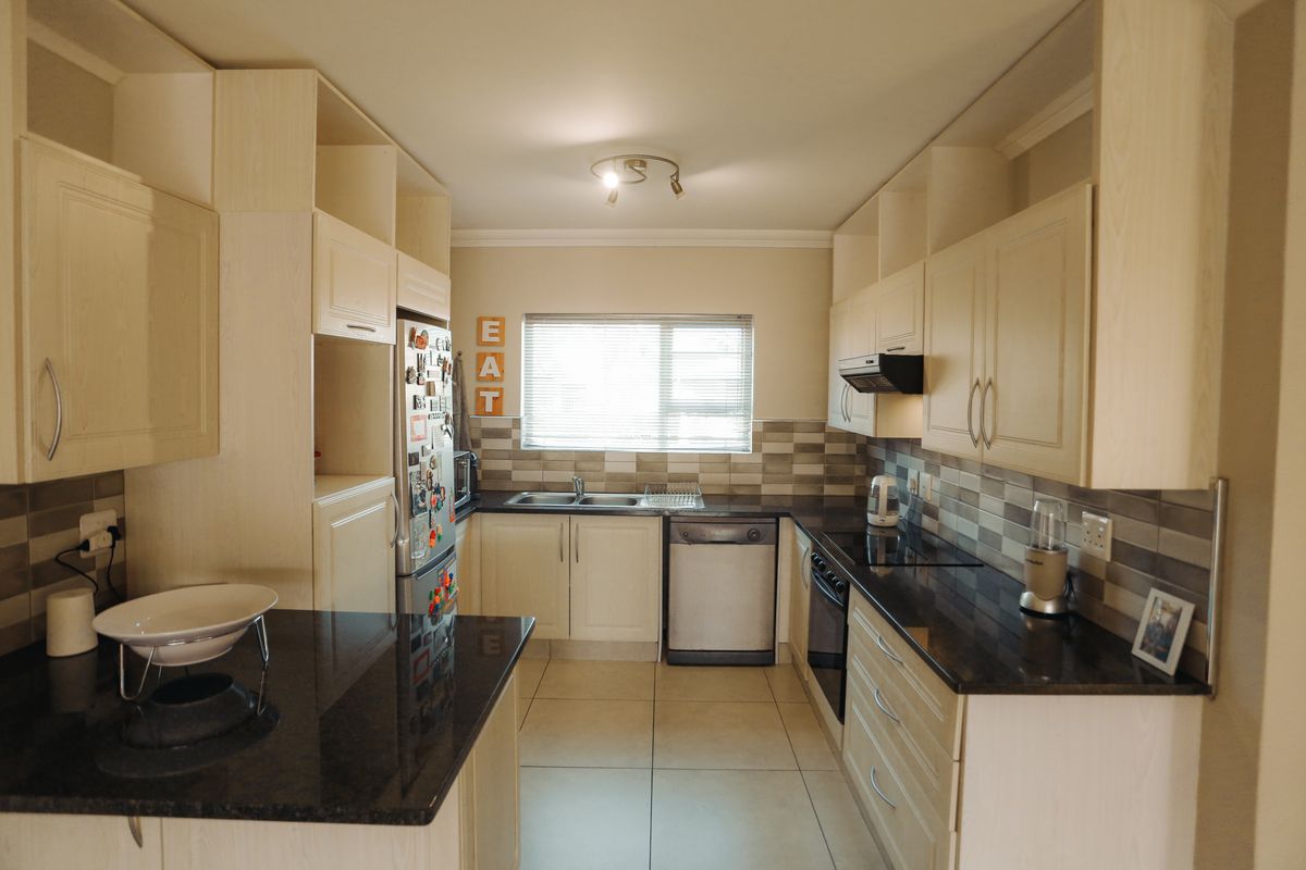 A functional kitchen featuring light-toned cabinetry, dark granite countertops, a tiled backsplash, and integrated appliances, offering a practical layout for daily cooking.