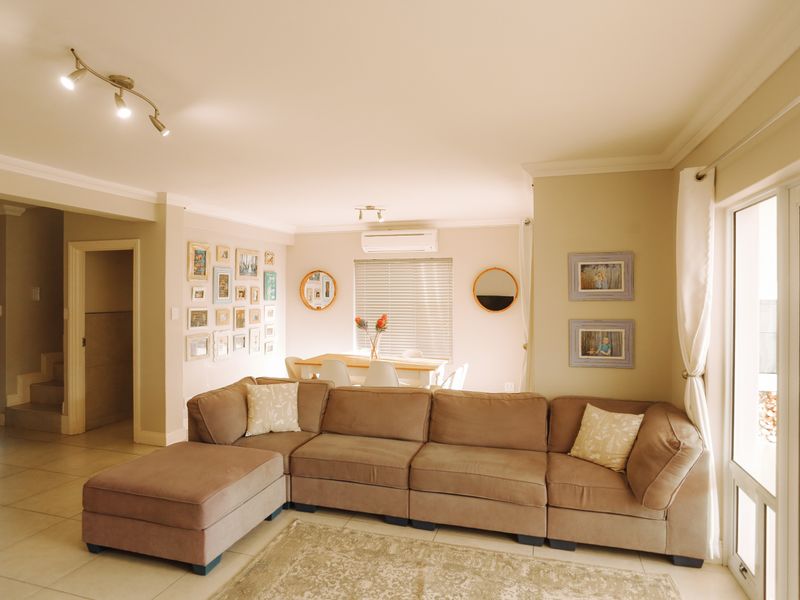 Spacious open-plan living and dining area featuring tiled floors, air conditioning, and large sliding glass doors providing natural light and access to the exterior.