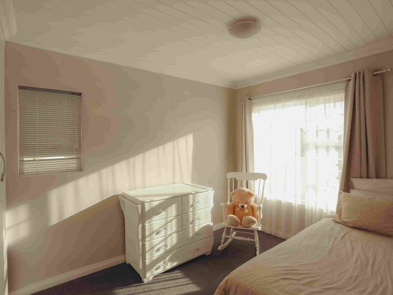 A cozy bedroom featuring carpeted flooring, a built-in wardrobe, and a distinctive tongue and groove ceiling with natural light from the window.