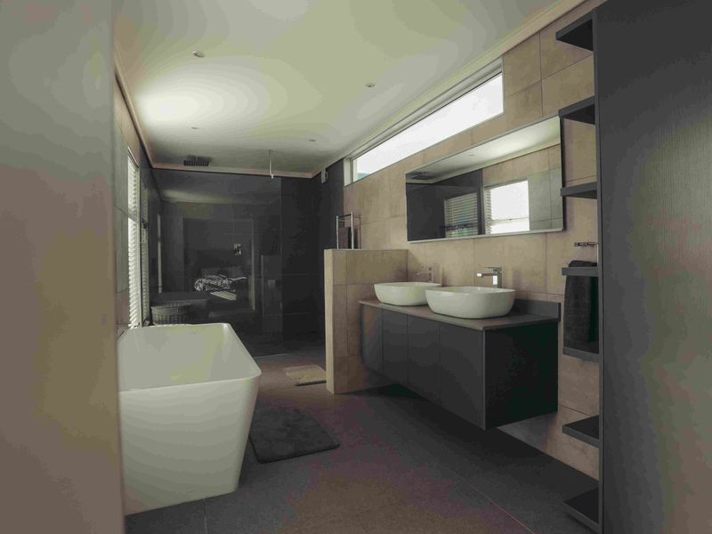 Modern bathroom featuring a sleek double vanity with vessel sinks, a freestanding bathtub, and a spacious walk-in shower with contemporary tiling.