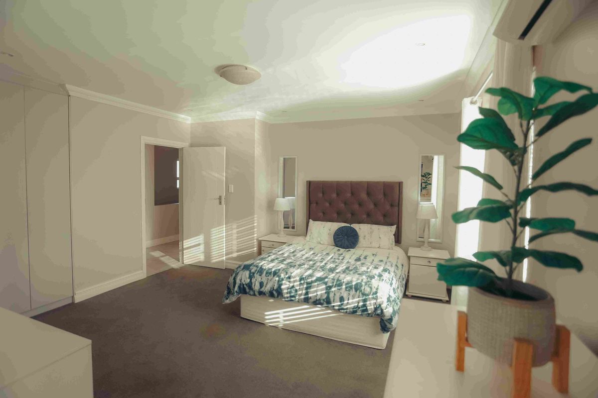 Spacious bedroom featuring neutral walls, carpeted flooring, built-in cupboards, and an integrated air conditioning unit.