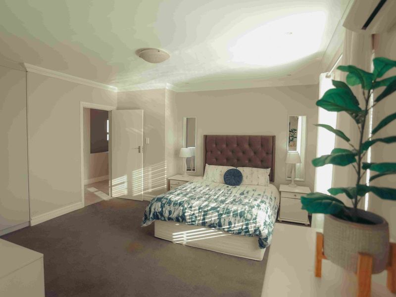 Spacious bedroom featuring neutral walls, carpeted flooring, built-in cupboards, and an integrated air conditioning unit.