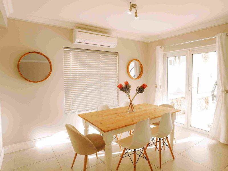 Bright dining area featuring tiled flooring, a wall-mounted air conditioning unit, and glass sliding doors providing access to the outdoor space.