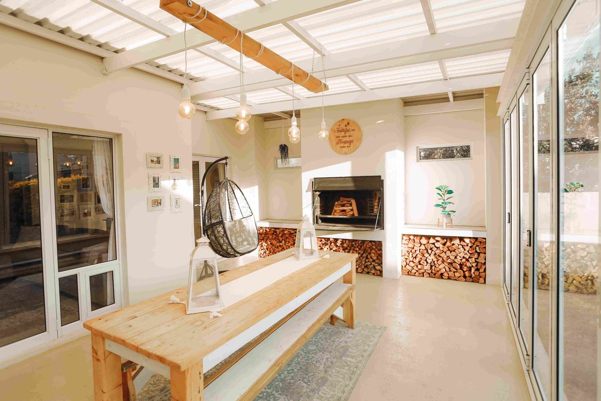 A bright, covered patio featuring a built-in fireplace, concrete flooring, and large sliding glass doors, perfect for outdoor entertaining.