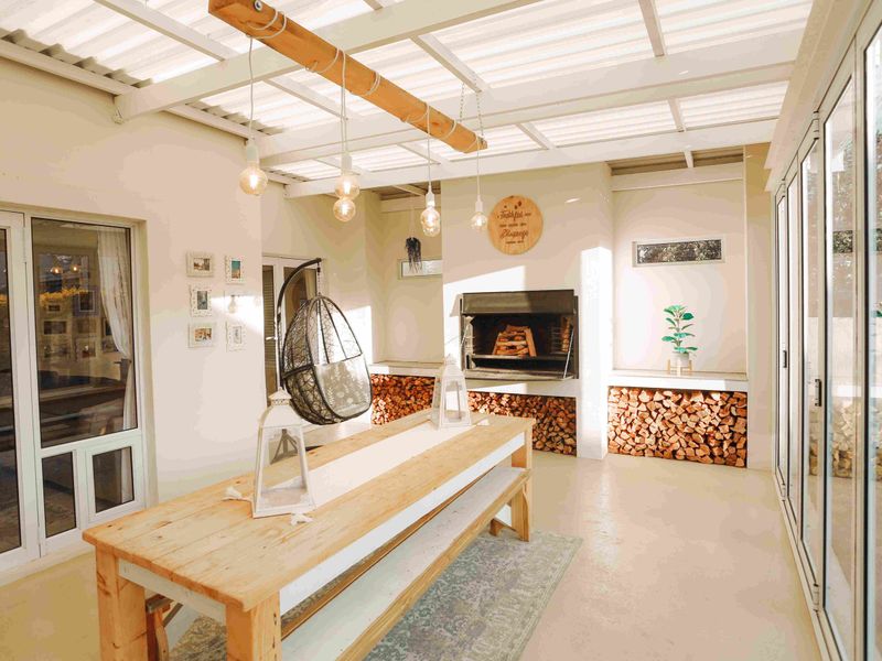 A bright, covered patio featuring a built-in fireplace, concrete flooring, and large sliding glass doors, perfect for outdoor entertaining.