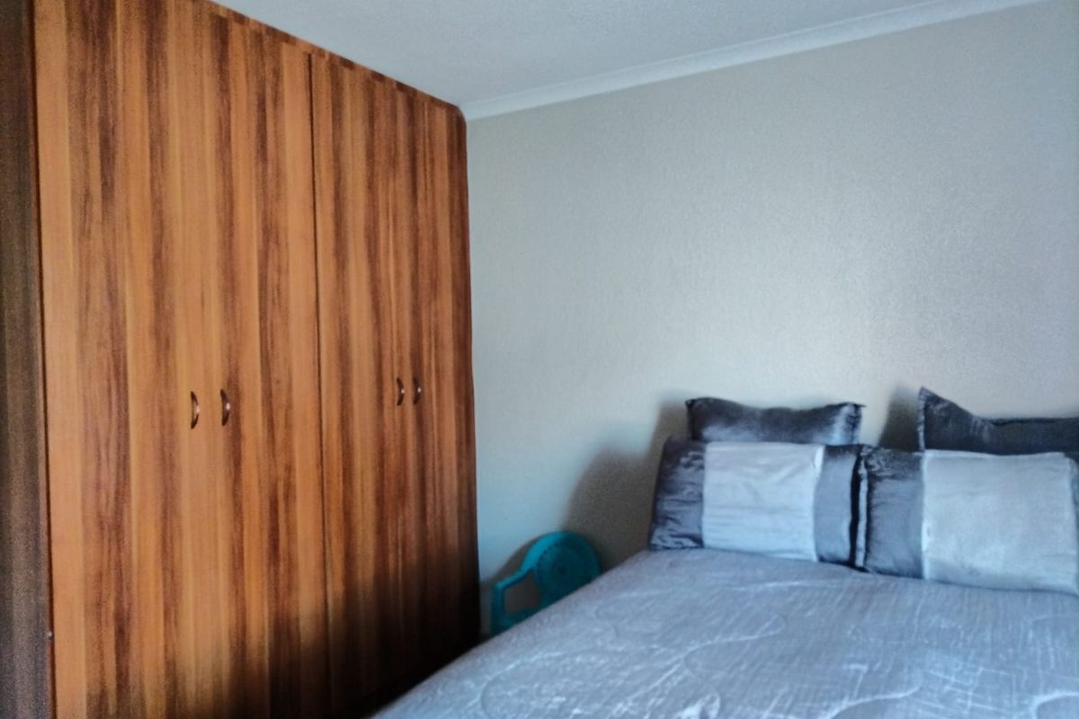 A bedroom featuring a large, wood-finish built-in wardrobe providing ample storage space.