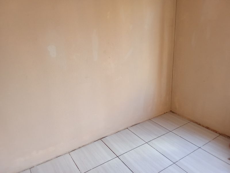 An empty room featuring light-colored floor tiles and unfinished wall surfaces, providing a blank canvas for renovation or interior design updates.