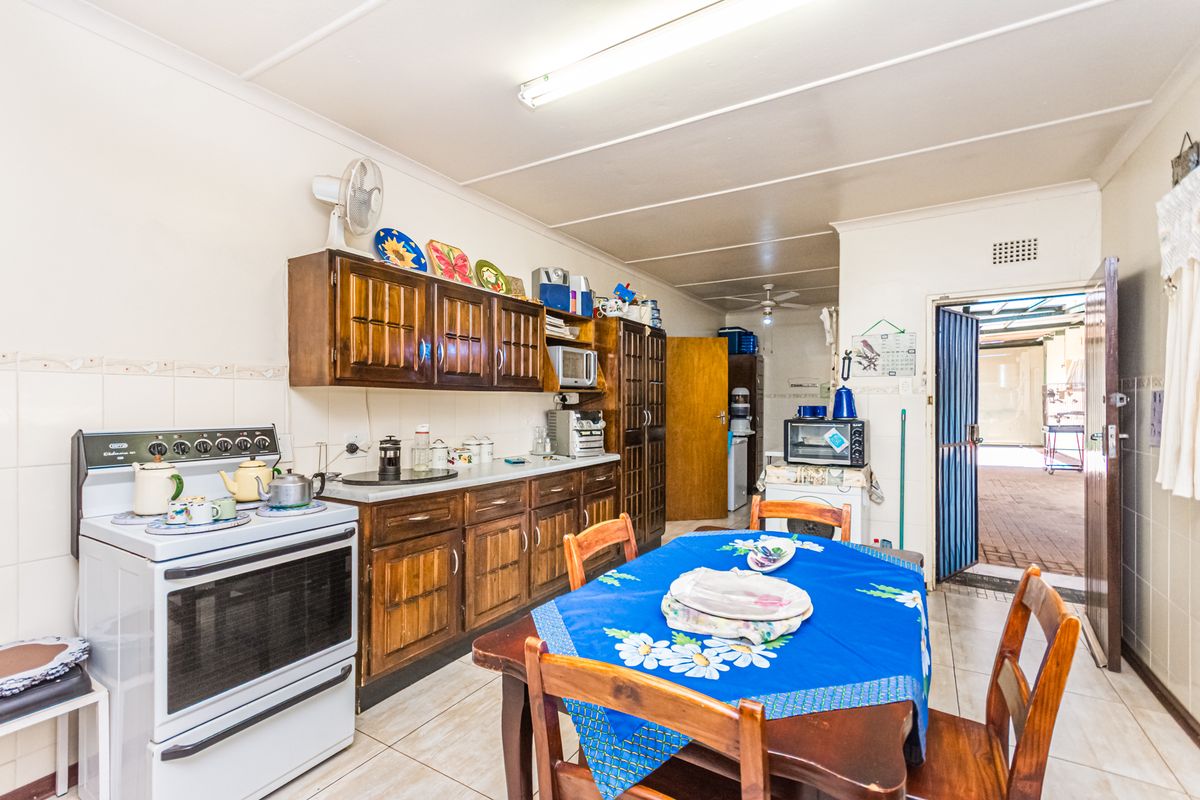 A functional kitchen and dining area featuring traditional wooden cabinetry, tiled flooring, and direct access to an outdoor area.
