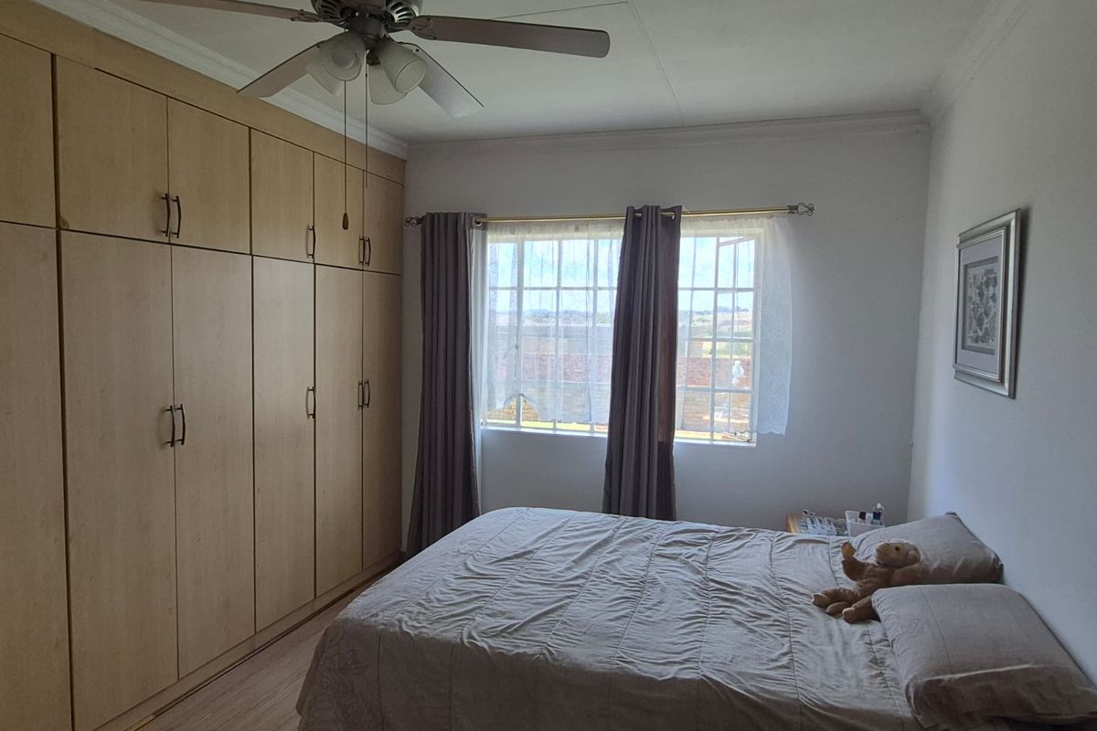 A bedroom featuring built-in wooden cabinetry, a ceiling fan, and natural light through a window.