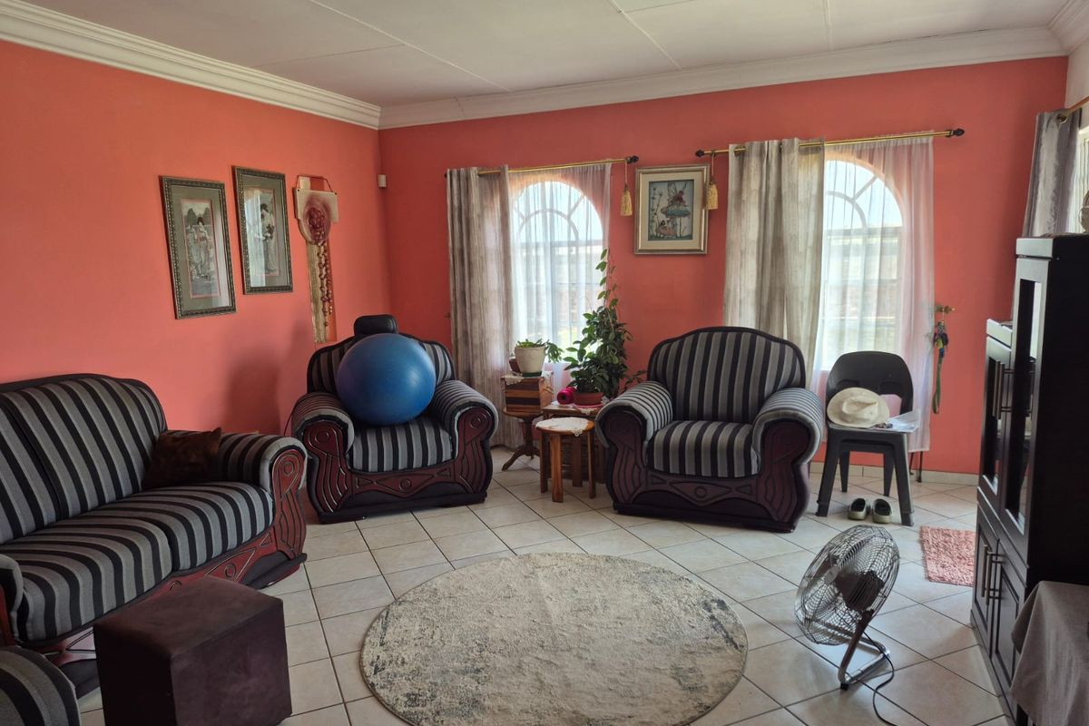 A living room featuring tiled flooring, arched windows with curtain rods, and crown molding, providing a functional and traditional living space.