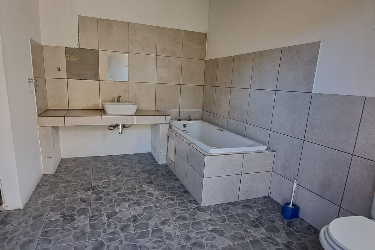 A functional bathroom featuring a built-in vanity with basin, a tiled bathtub, a separate shower enclosure, and a standard toilet.
