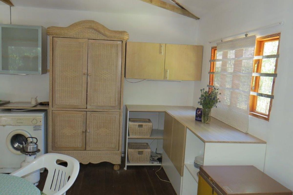 A functional kitchen area featuring built-in cabinetry, timber flooring, and exposed ceiling rafters, providing a practical workspace within the farm property.