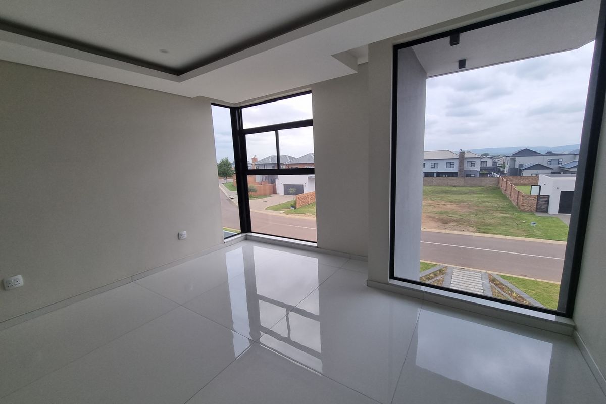 A bright, modern, and empty living area featuring large format floor tiles, recessed ceiling details, and expansive floor-to-ceiling windows with neighbourhood views.