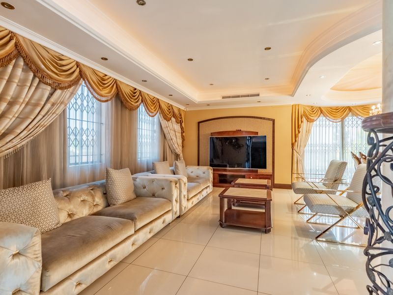 Spacious living room featuring polished tiled flooring, recessed ceiling lighting with cove details, and a built-in media unit.