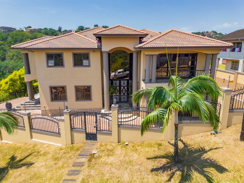 A double-story residential property featuring a tiled roof, decorative columns, and secure wrought iron perimeter fencing with integrated electric security wires.