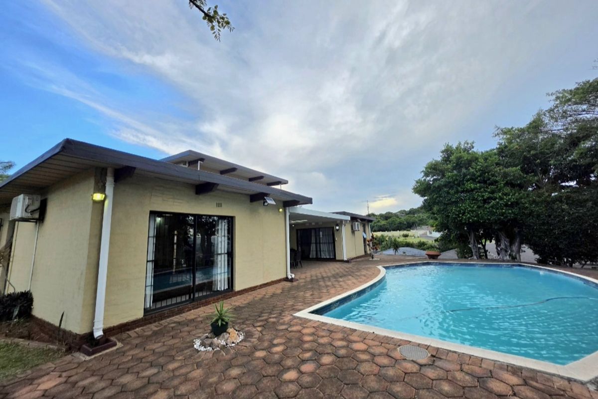 Rear exterior view featuring a swimming pool, paved patio area, and direct access to the home through sliding glass doors.