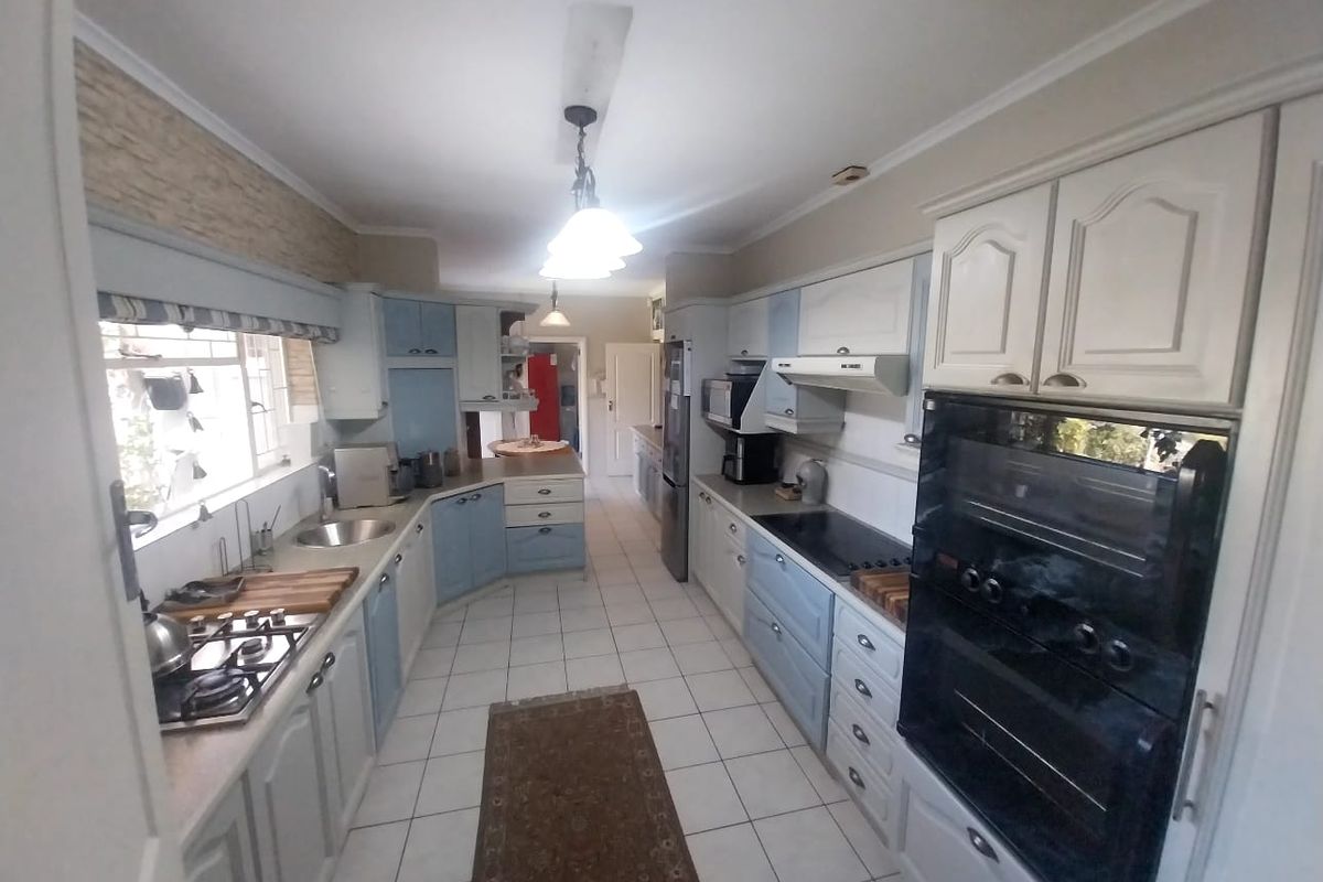 A functional kitchen featuring built-in cabinetry, a gas hob, integrated oven, and tiled flooring, offering a practical layout for daily meal preparation.