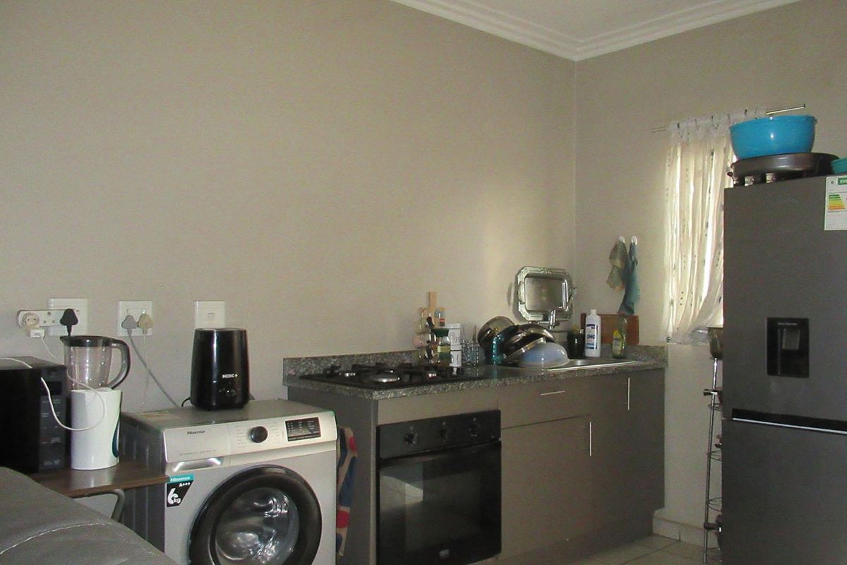 Compact kitchen area featuring built-in cabinetry, granite countertops, a gas hob, and an integrated oven, providing essential cooking and utility space.