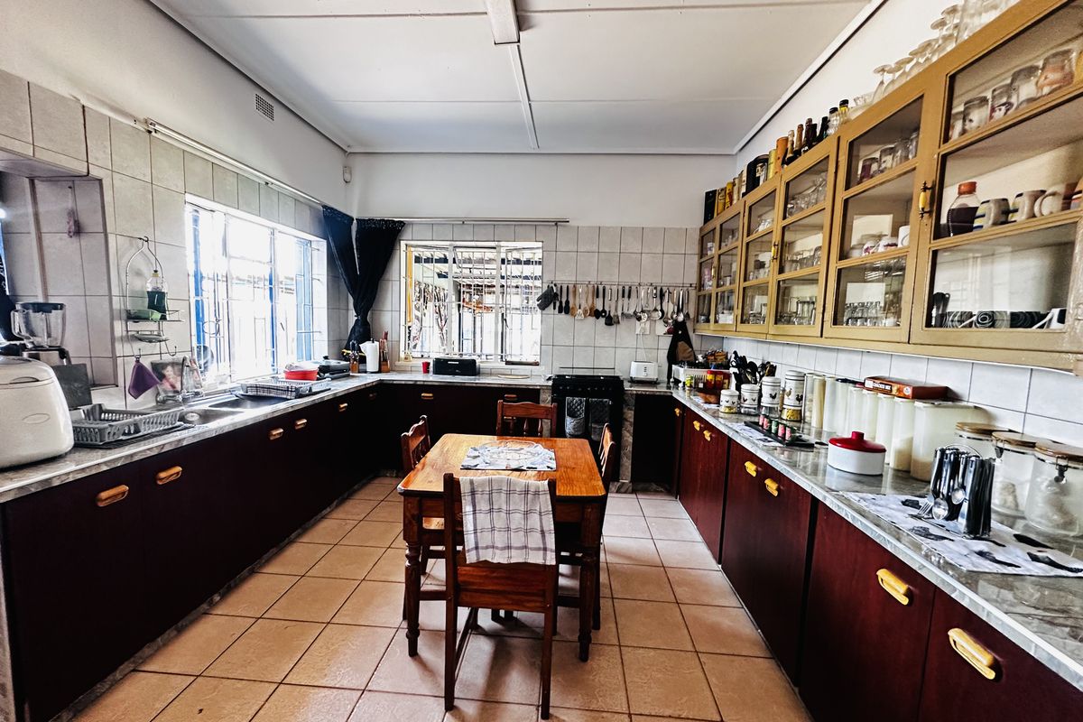 Spacious kitchen featuring extensive built-in cabinetry, tiled flooring, and a functional layout with ample counter space and integrated storage solutions.
