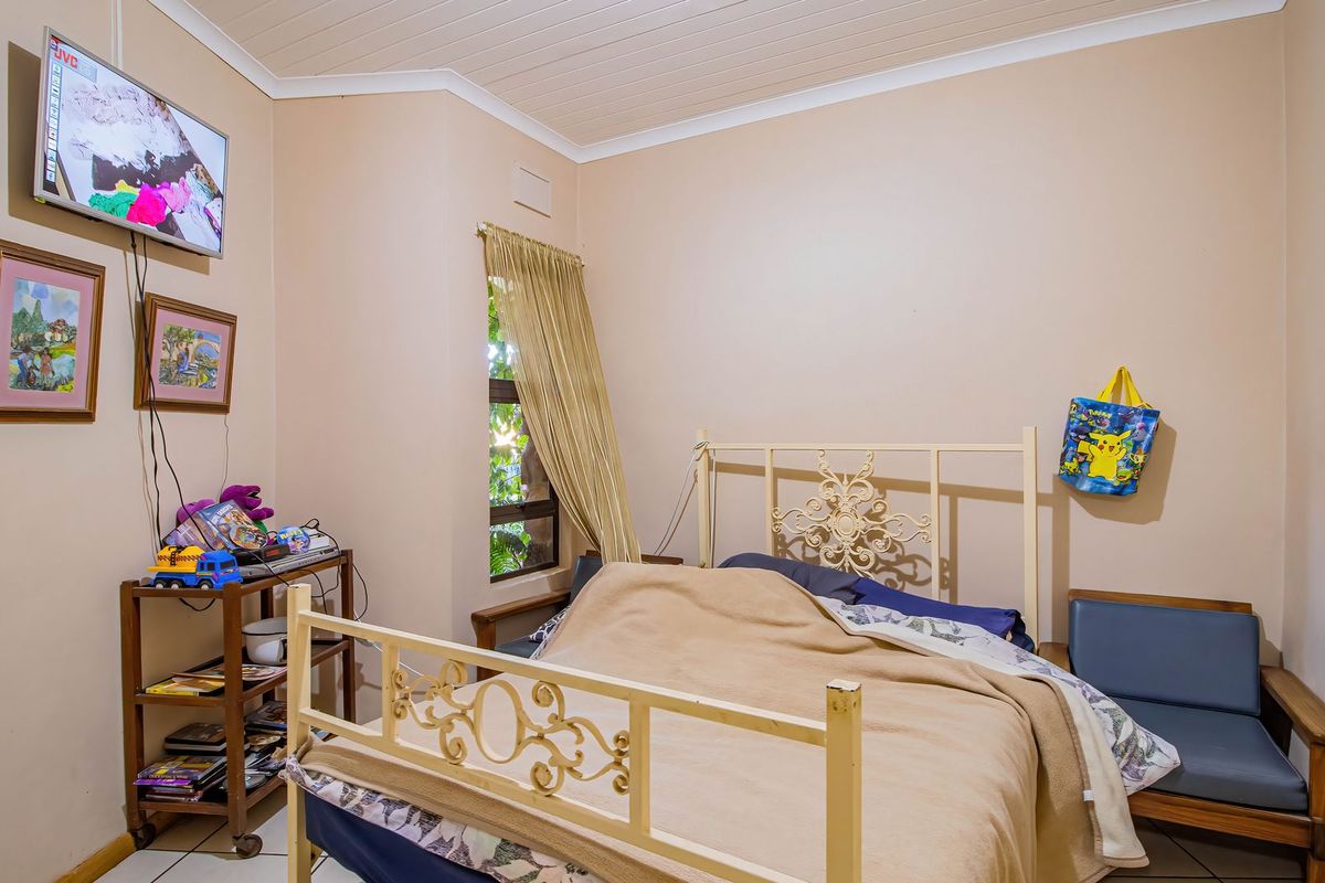 A functional bedroom featuring tiled flooring, a timber ceiling with cornice detailing, and a window providing natural light.