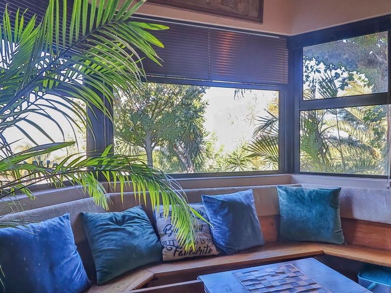 A cozy living area featuring a custom built-in corner bench and large wrap-around windows that provide ample natural light and garden views.